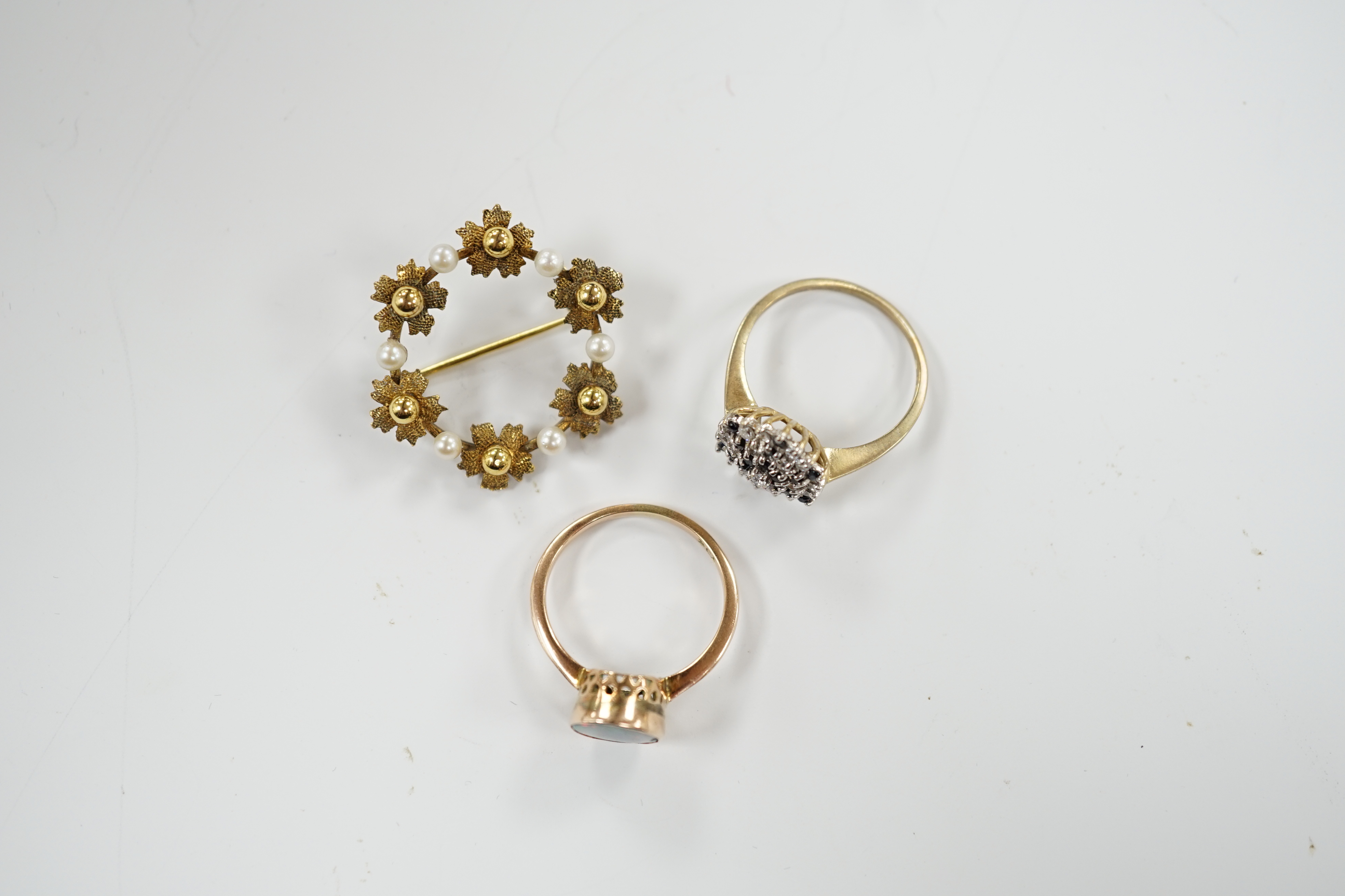 A 9ct gold and two colour sapphire cluster set dress ring, one other 9ct and opal ring and a 9ct gold and cultured pearl set open work circular brooch, gross weight 8.5 grams.